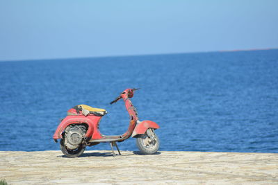 Bicycle by sea against clear blue sky