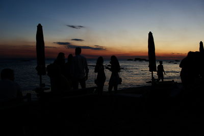 Silhouette people on beach against sky during sunset