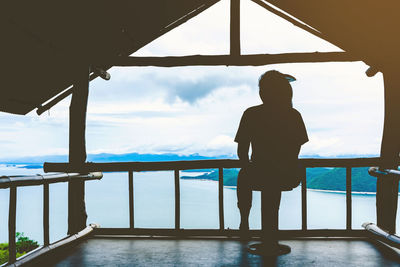 Rear view of man looking at sea against sky