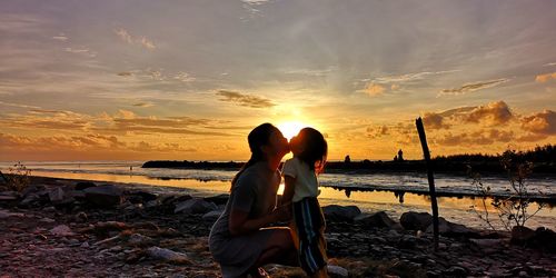 Woman on beach against sky during sunset