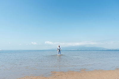 One mid adult man practices taekwondo on the beach at morning