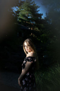 Smiling young woman standing against trees