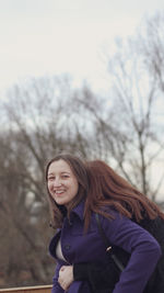 Portrait of a smiling young woman against bare trees