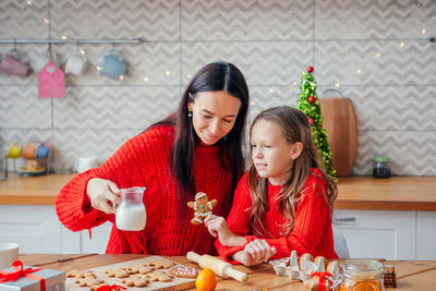 Smiling mother and daughter preparing gingerbread cookies at home
