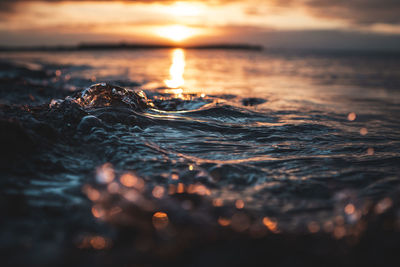 Small waves breaking onto the beach reflecting the sunset.