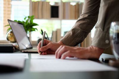 Midsection of man using laptop on table