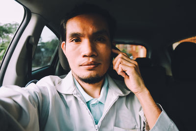 Portrait of mid adult man talking on mobile phone while sitting in car
