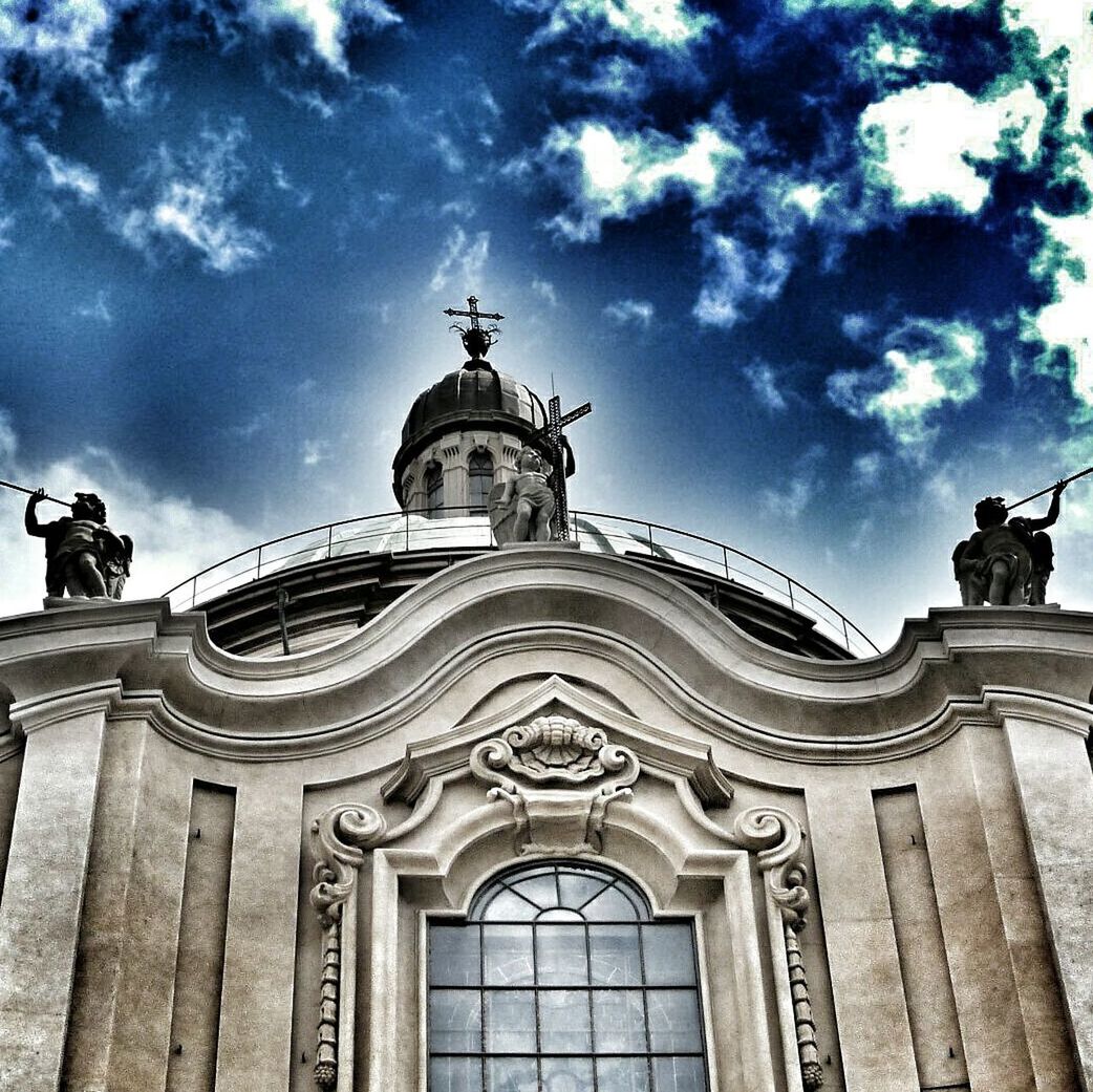 low angle view, architecture, built structure, place of worship, religion, building exterior, sky, church, spirituality, cloud - sky, human representation, cathedral, statue, arch, sculpture, art and craft, history, famous place