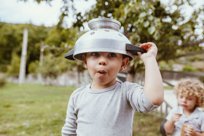 Playful boy wearing colander while playing on meadow