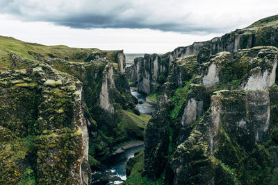 Scenic view of waterfall by mountains against sky