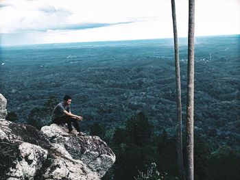 Man sitting on rock looking at mountain