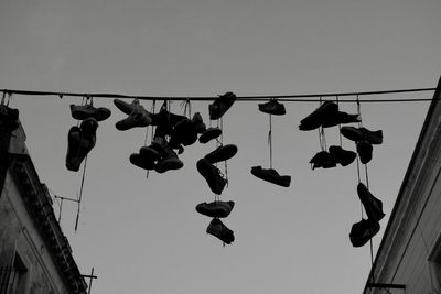 Low angle view of shoes hanging against clear sky