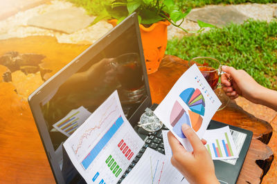 Cropped hand of businesswoman holding graph paper while having black tea