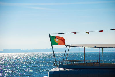 Flag on boat against sea and clear sky