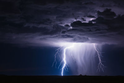 A dramatic lightning bolt illuminates an approaching thunderstorm near holbrook, arizona.