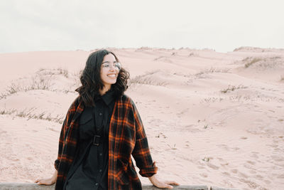 Portrait of young woman standing at desert