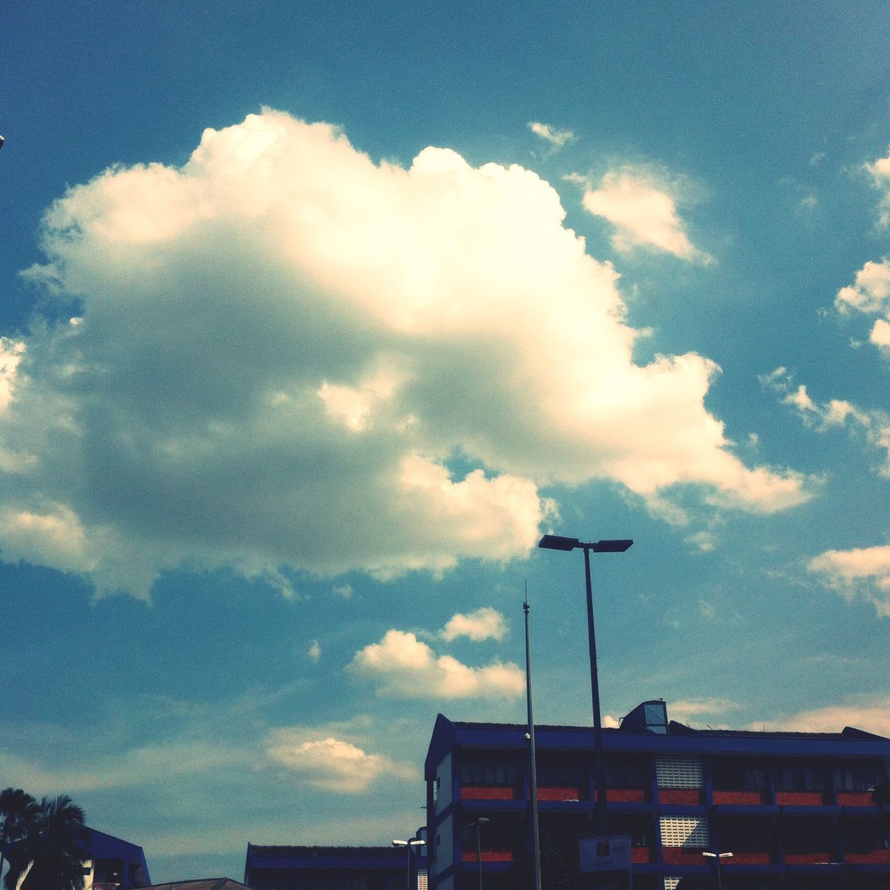 sky, building exterior, cloud - sky, built structure, architecture, low angle view, cloudy, cloud, house, residential structure, residential building, street light, high section, blue, city, building, outdoors, weather, no people, nature