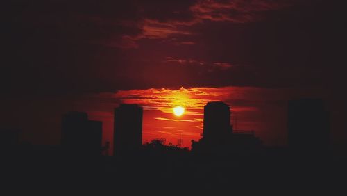 Silhouette city by sea against sky during sunset