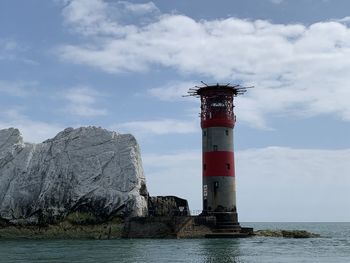 Lighthouse by sea against sky