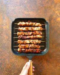 High angle view of person holding meat on barbecue grill