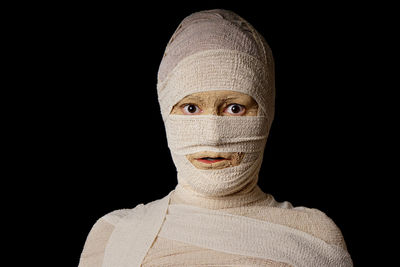 Portrait of woman in mummy costume against black background