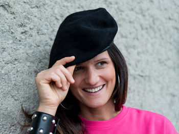 Close up portrait of smiling girl wearing a black beret and a fuchsia dress and a studded bracelet