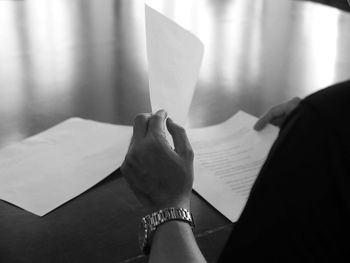 Cropped hand holding paper at table