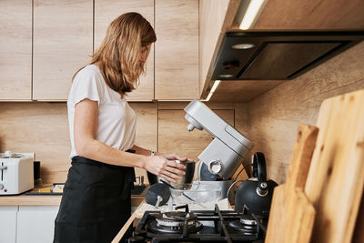 Woman cooking at preparing food, using food processor,