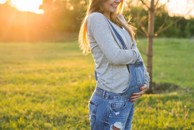 Midsection of woman with arms raised on field