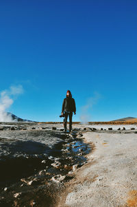 Man standing on desert against clear blue sky