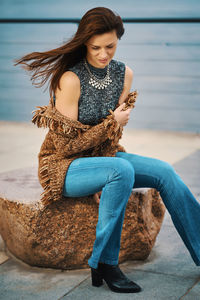 Full length of woman sitting by sea