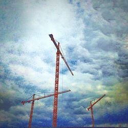 Low angle view of crane against cloudy sky