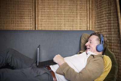 Senior man in headphones having video call on tablet