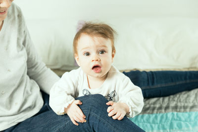 Cute baby girl sitting on sofa at home