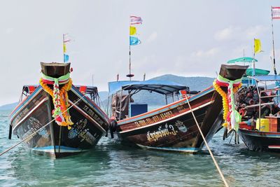 Fishing boats moored in sea against sky