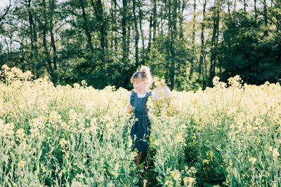 Young girl walking through a flower field with a basket at sunset