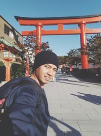 Portrait of smiling young woman standing against built structure