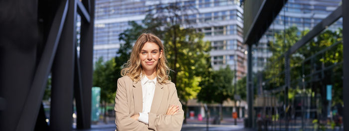 Portrait of young woman standing in city