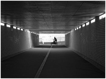 Rear view of man walking in tunnel