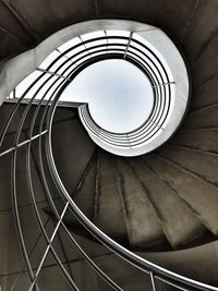 Sky seen amidst spiral stairway from below