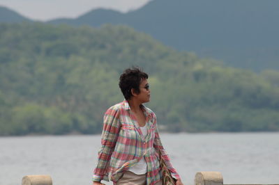 Woman looking at sea while standing against mountain