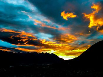 Scenic view of silhouette mountains against dramatic sky during sunset