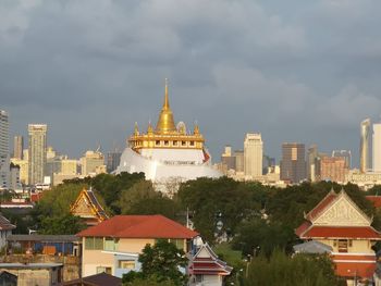 View of buildings in city against cloudy sky