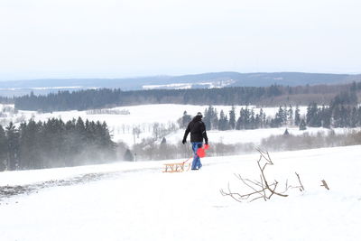 Full length of man on snowy landscape against sky