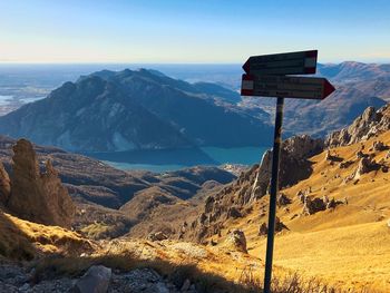 Close-up of information sign against mountains and sky