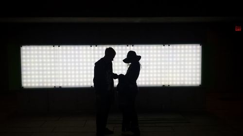 Silhouette couple standing against window