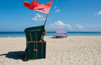 Deck chairs on beach against sky