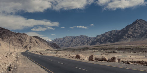 Road leading towards mountains against sky