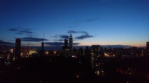 Illuminated cityscape against blue sky