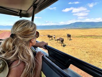 Side view of woman looking at wildebeest